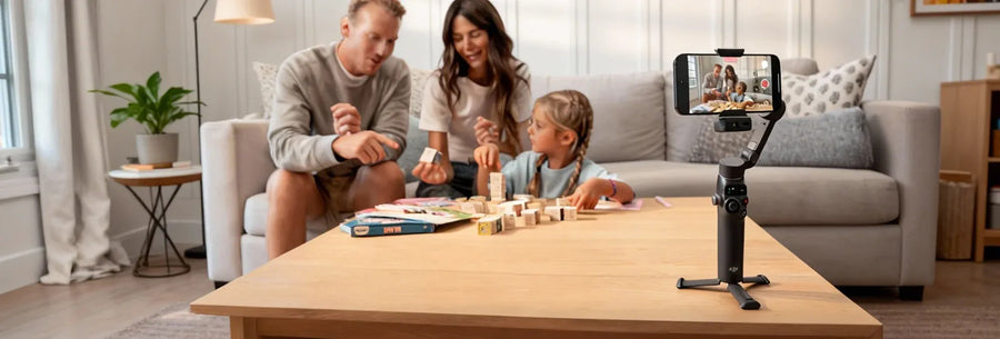 Family playing a board game in a living room with a smartphone on a gimbal. Sold by an Authorized DJI Retailer.